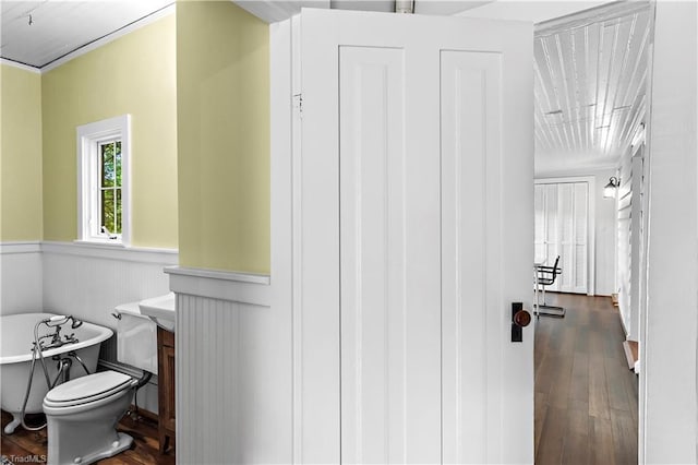 bathroom with a freestanding bath, wood-type flooring, a wainscoted wall, and vanity