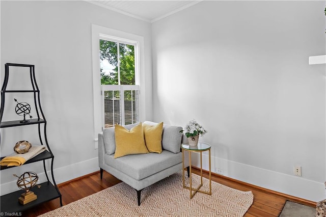 sitting room with wood finished floors, ornamental molding, and baseboards