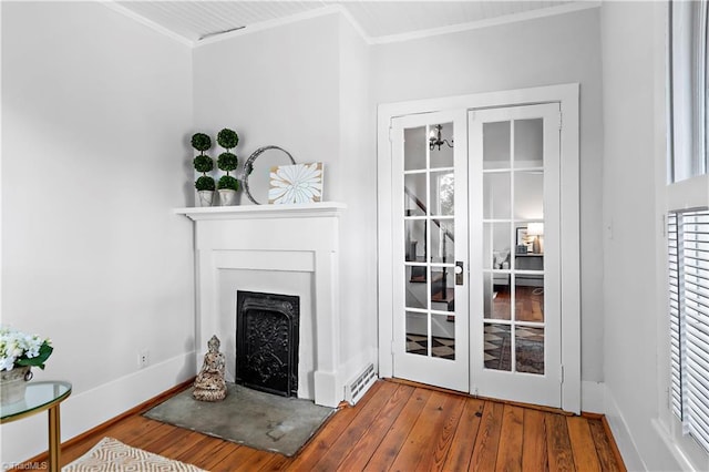 living area with crown molding, wood-type flooring, a fireplace, baseboards, and french doors
