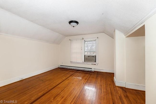 additional living space with baseboard heating, a textured ceiling, lofted ceiling, and wood-type flooring