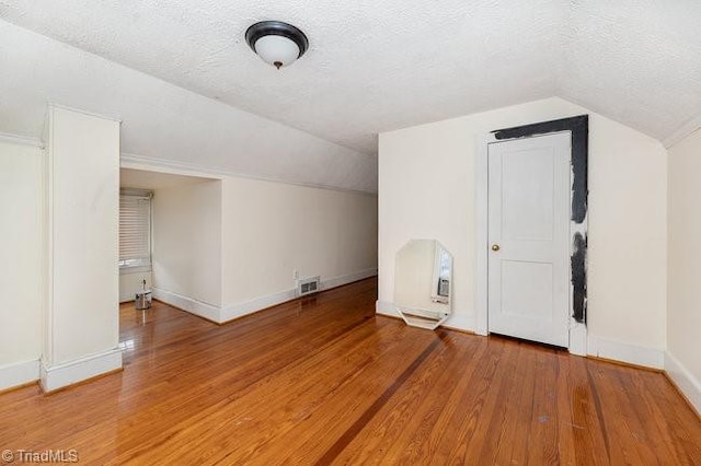 bonus room with visible vents, baseboards, a textured ceiling, and wood finished floors