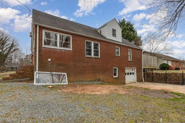 back of property with brick siding, an attached garage, and concrete driveway