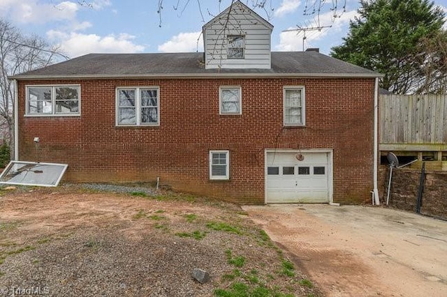 rear view of property with brick siding, concrete driveway, and an attached garage