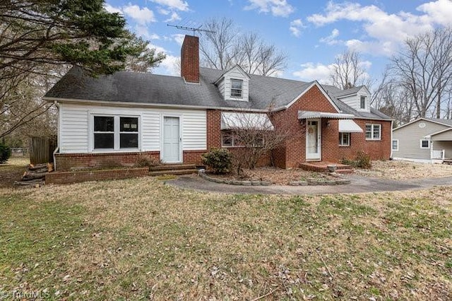 view of front of property with brick siding, a chimney, and a front yard