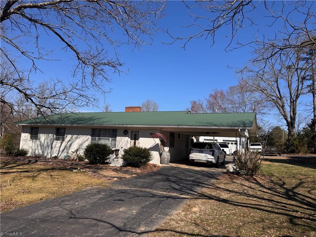 view of front of house featuring a carport, aphalt driveway, and a chimney