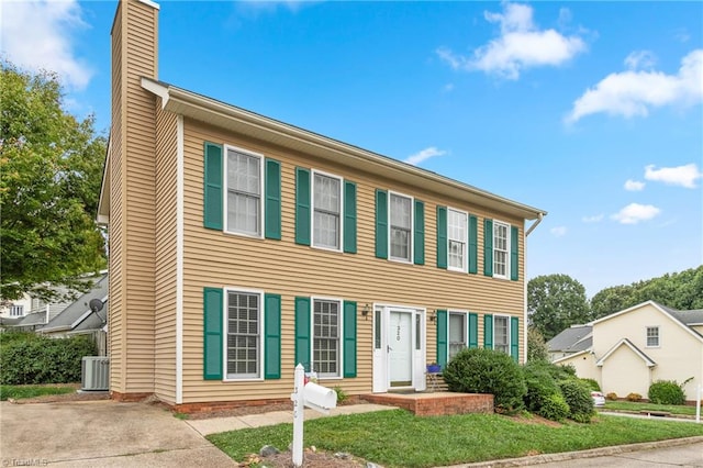 colonial home featuring central AC and a front yard