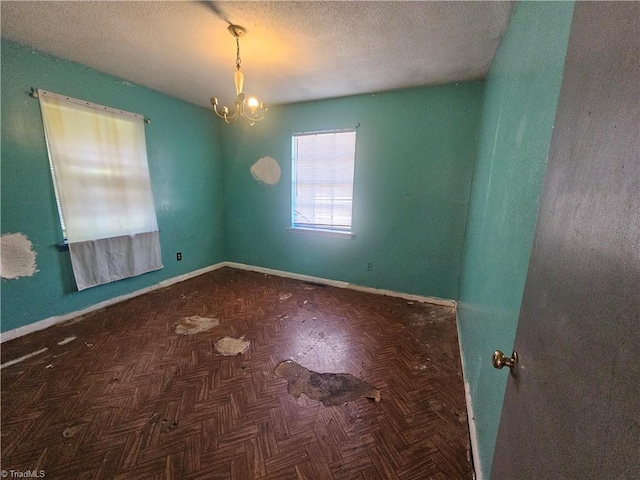 empty room featuring an inviting chandelier, dark parquet flooring, and a textured ceiling