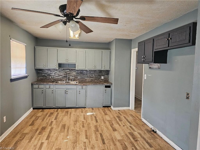 kitchen featuring gray cabinets, sink, light hardwood / wood-style flooring, and backsplash