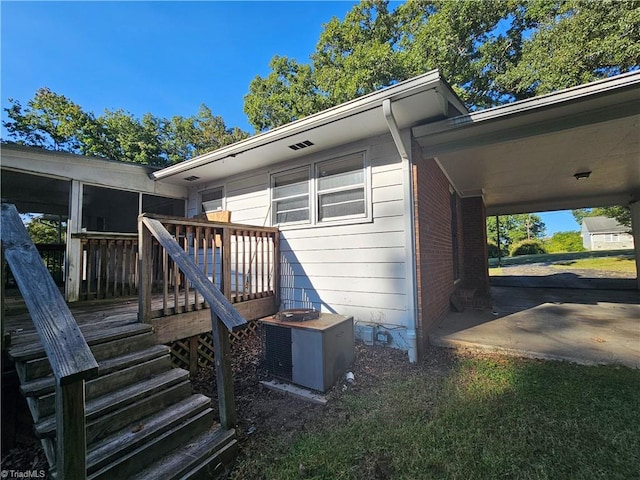 back of property featuring a wooden deck, a sunroom, and central AC