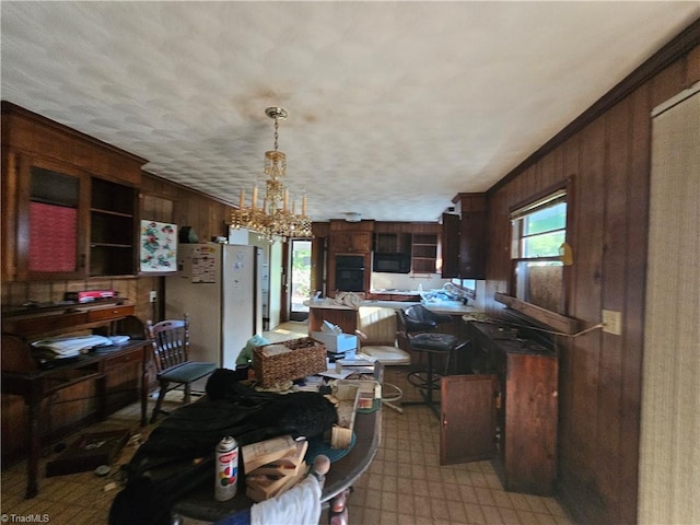 kitchen featuring dark brown cabinetry, an inviting chandelier, hanging light fixtures, and ornamental molding