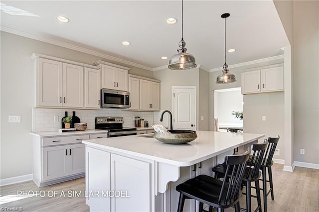 kitchen with appliances with stainless steel finishes, decorative light fixtures, white cabinetry, an island with sink, and backsplash