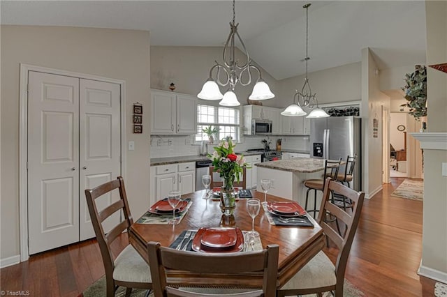 dining space with high vaulted ceiling, baseboards, and wood finished floors