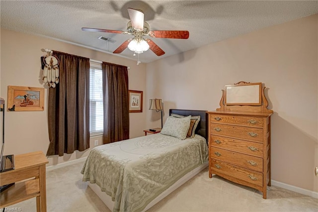 bedroom featuring visible vents, light carpet, a ceiling fan, a textured ceiling, and baseboards