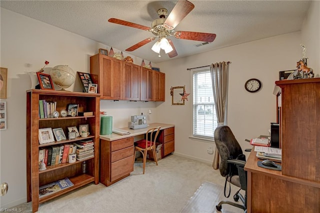 home office with visible vents, baseboards, ceiling fan, light colored carpet, and a textured ceiling