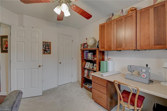 office featuring a ceiling fan, light colored carpet, and a textured ceiling