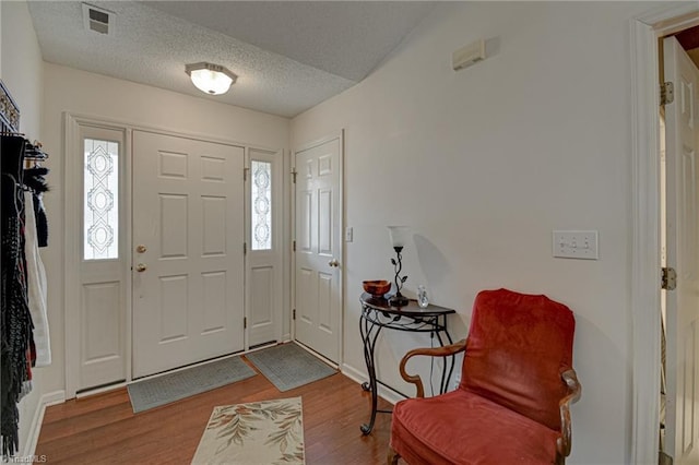 entrance foyer with visible vents, a healthy amount of sunlight, a textured ceiling, and wood finished floors