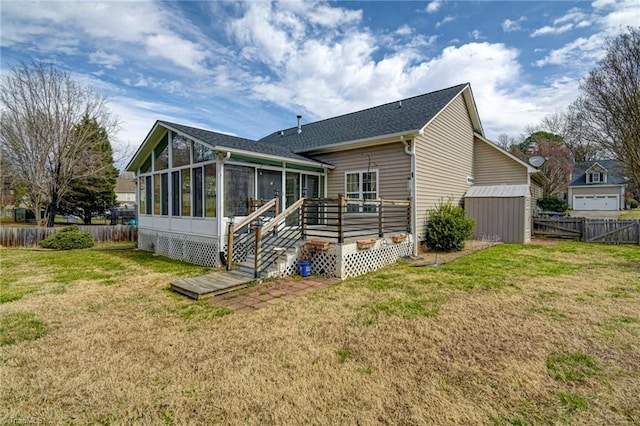 rear view of property with a wooden deck, fence, a lawn, and a sunroom