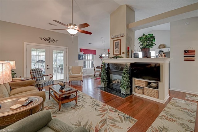 living area featuring french doors, lofted ceiling, wood finished floors, and a tile fireplace