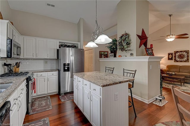 kitchen featuring dark wood finished floors, a kitchen island, visible vents, and stainless steel appliances