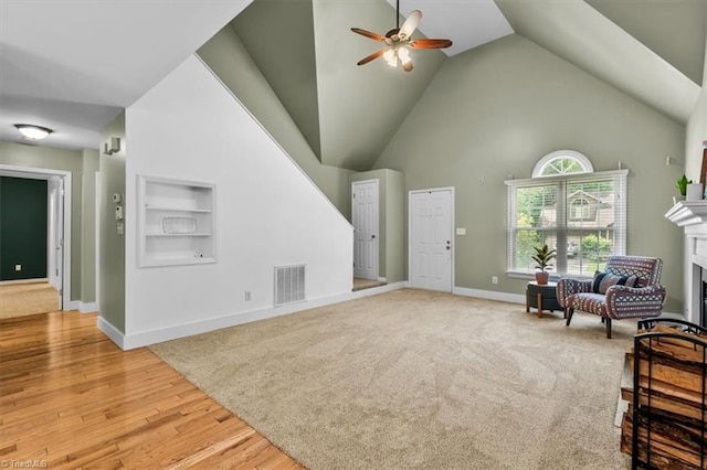living area featuring a fireplace, visible vents, baseboards, ceiling fan, and built in shelves