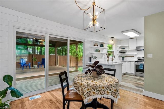 dining room featuring a healthy amount of sunlight, an inviting chandelier, visible vents, and light wood-style floors