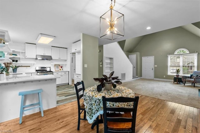 dining room featuring lofted ceiling, baseboards, visible vents, a chandelier, and light wood-type flooring