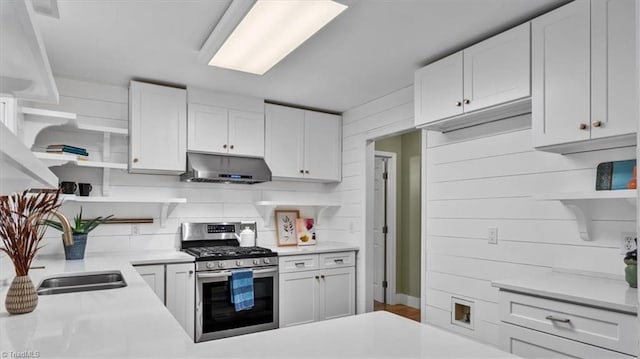 kitchen with open shelves, stainless steel gas stove, under cabinet range hood, backsplash, and light countertops