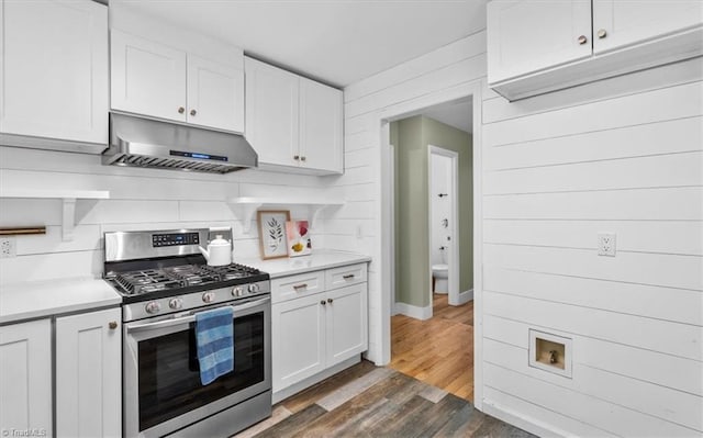 kitchen with under cabinet range hood, light countertops, dark wood-style flooring, and stainless steel range with gas cooktop