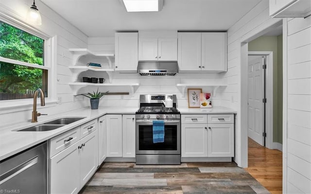 kitchen with a sink, open shelves, under cabinet range hood, light countertops, and appliances with stainless steel finishes
