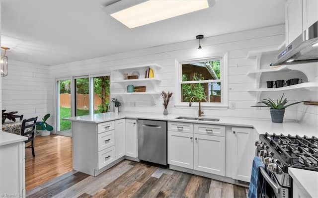 kitchen featuring open shelves, appliances with stainless steel finishes, a peninsula, and a sink