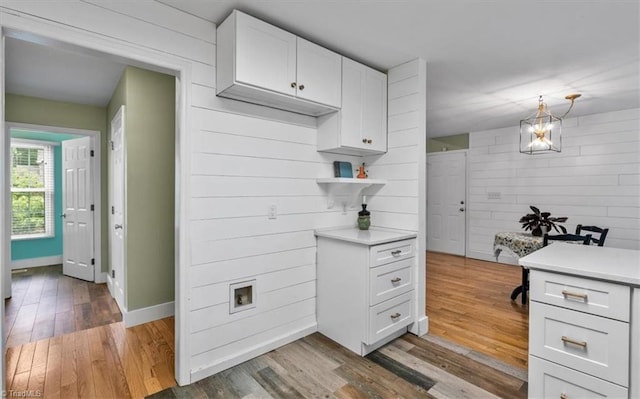 kitchen featuring baseboards, open shelves, wood finished floors, light countertops, and white cabinets