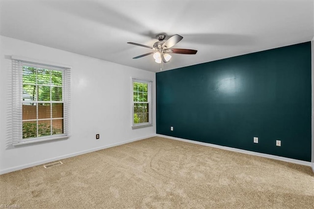 carpeted empty room with ceiling fan, baseboards, and visible vents