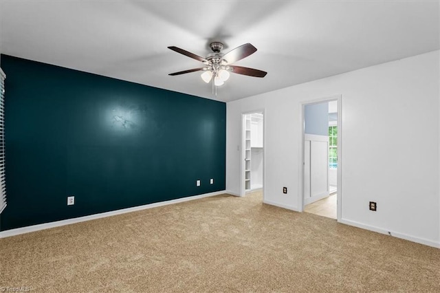 carpeted empty room with ceiling fan and baseboards