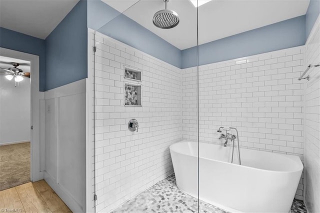 full bath with tile walls, ceiling fan, tiled shower, a freestanding bath, and wood finished floors