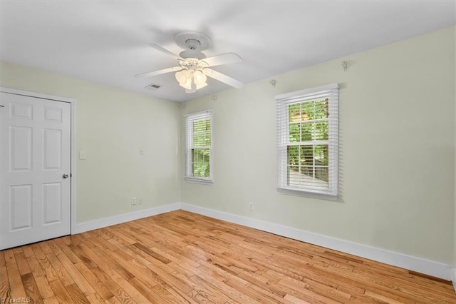 spare room featuring ceiling fan, baseboards, visible vents, and light wood-style floors