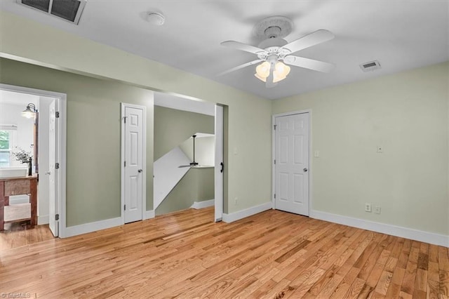 empty room with baseboards, ceiling fan, light wood finished floors, and visible vents