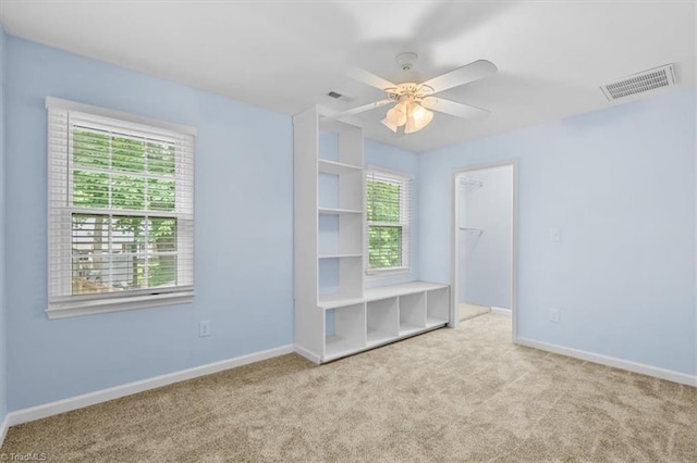 unfurnished room with ceiling fan, carpet, baseboards, and visible vents