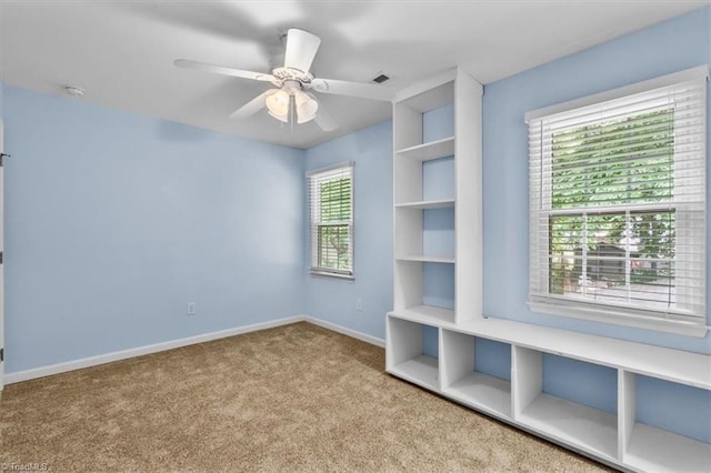 carpeted empty room featuring baseboards, ceiling fan, and visible vents