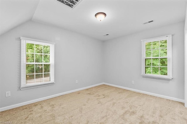unfurnished room with carpet flooring, visible vents, baseboards, and vaulted ceiling