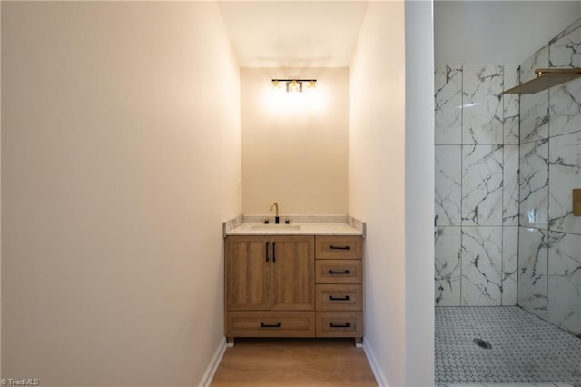 bathroom featuring hardwood / wood-style flooring, vanity, and a tile shower