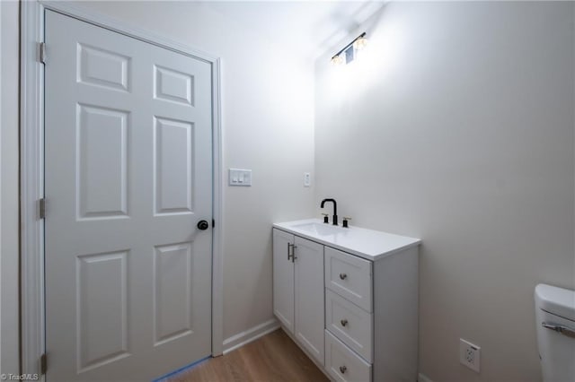 bathroom with hardwood / wood-style floors, vanity, and toilet