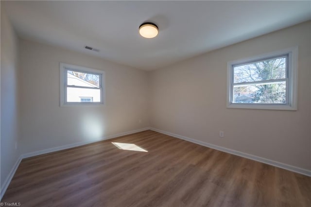 unfurnished room featuring dark hardwood / wood-style flooring and plenty of natural light