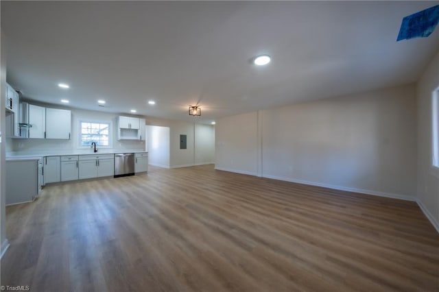 unfurnished living room featuring electric panel, light hardwood / wood-style flooring, and sink