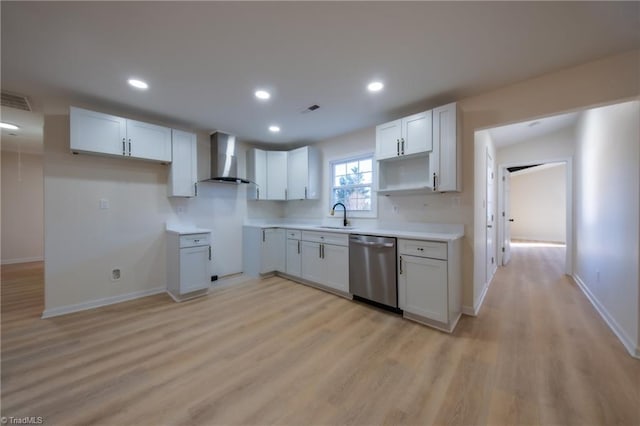 kitchen with white cabinets, sink, light hardwood / wood-style flooring, stainless steel dishwasher, and wall chimney exhaust hood