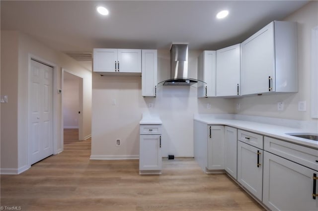 kitchen featuring light hardwood / wood-style floors, white cabinetry, and wall chimney exhaust hood