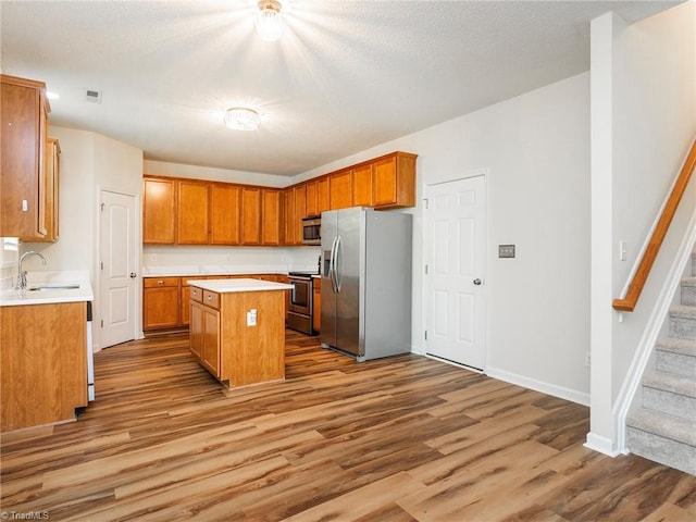 1307 Montreux Ct, Mebane, NC 27302 - kitchen featuring a center island, wood finished floors, a sink, stainless steel appliances, and light countertops
