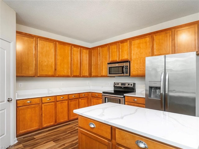 1307 Montreux Ct, Mebane, NC 27302 - kitchen featuring a textured ceiling, light stone counters, brown cabinets, appliances with stainless steel finishes, and dark wood-style floors