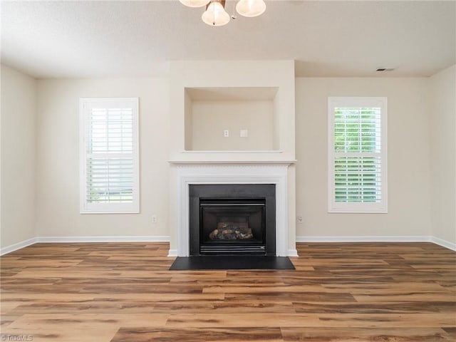 1307 Montreux Ct, Mebane, NC 27302 - unfurnished living room with baseboards, a fireplace with flush hearth, visible vents, and wood finished floors