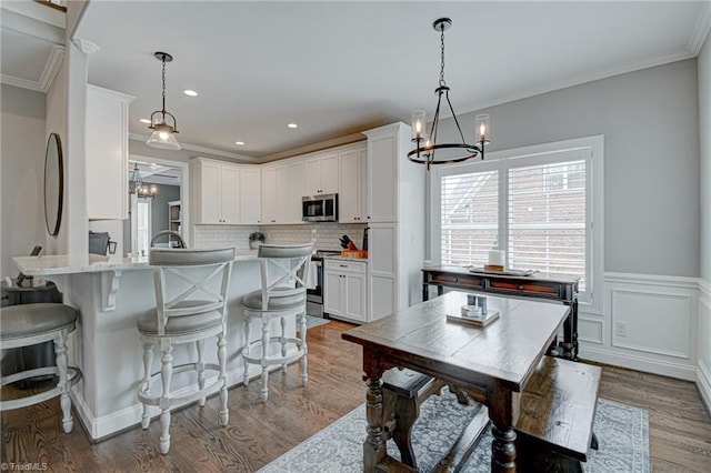 231 Plumstead Ln, Clemmons, NC 27012 - kitchen featuring a chandelier, stainless steel appliances, healthy amount of natural light, a kitchen bar, and crown molding