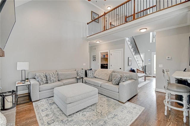 231 Plumstead Ln, Clemmons, NC 27012 - living room featuring a towering ceiling, stairway, crown molding, light wood-type flooring, and baseboards